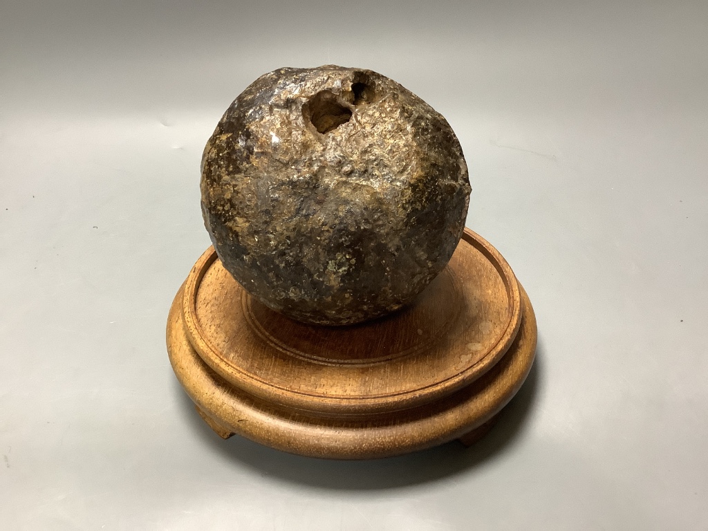 A 17 / 18th century canon ball, on hardwood stand